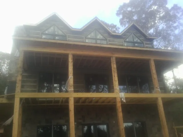 Dormers and porch framing on a large log home under construction — Roof Coating work by our crew in Ellsworth